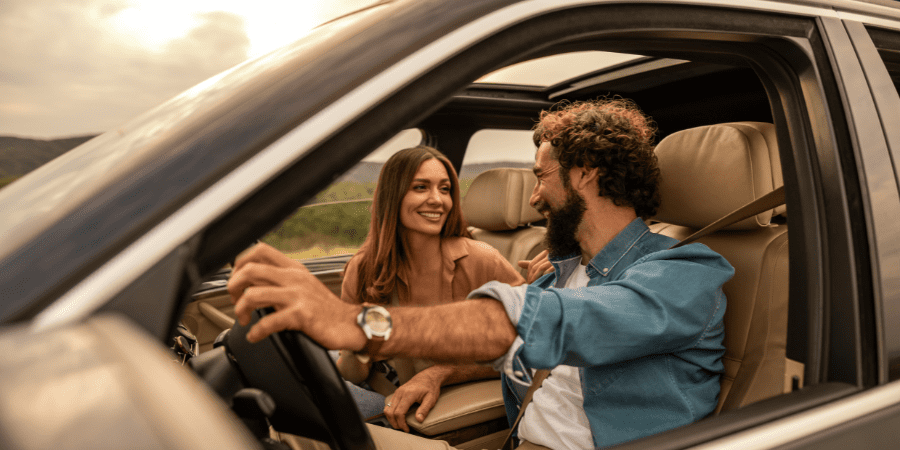 Interior view of a male and female in a car driving.