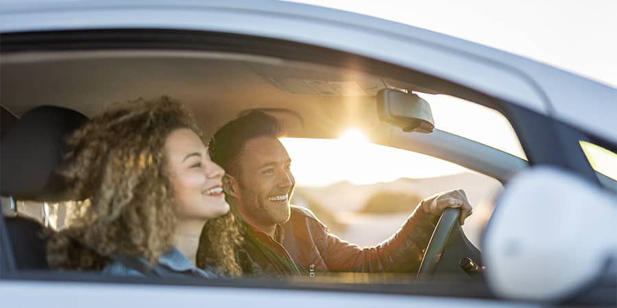 A young couple happily driving during a sunset.