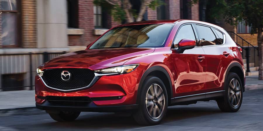 A red, shiny Nissan SUV in motion.