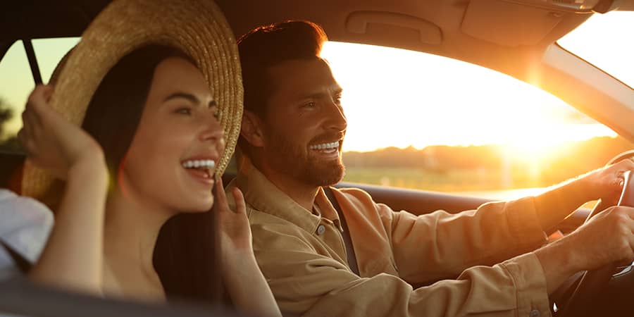 A young couple happily driving during a sunset.