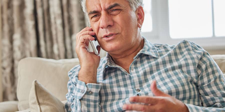 A distressed elderly man using a smartphone.