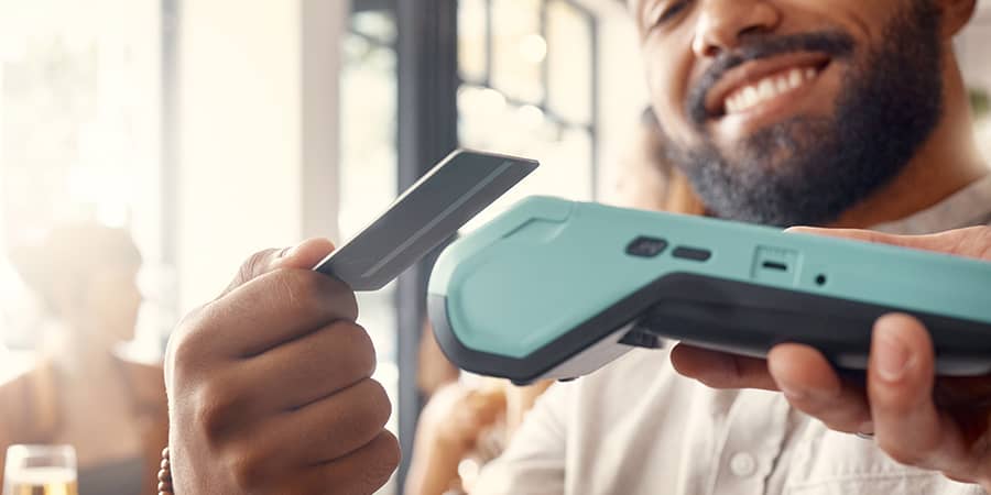 A man tapping a credit card on a machine.