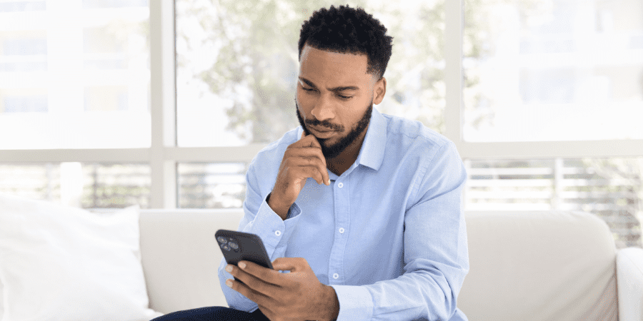 A middle-aged man sitting on a couch holding a smart phone.