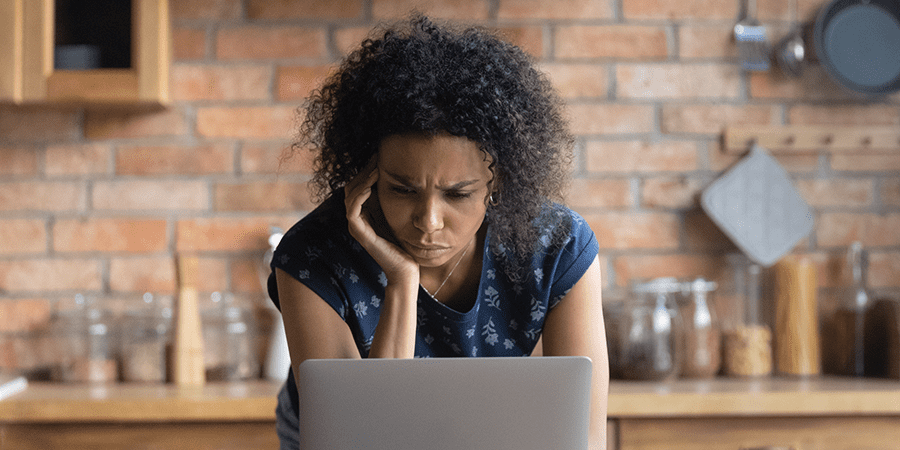 A distressed woman looking at a laptop.