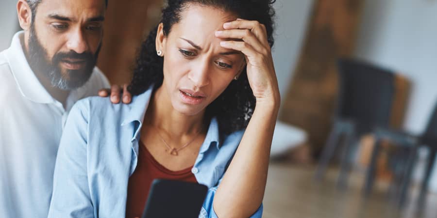 A couple under distress while looking at a smartphone.