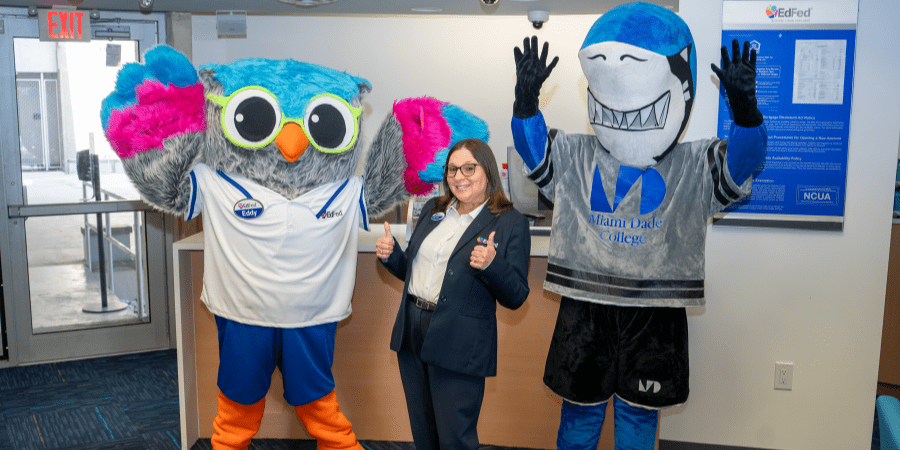 An EdFed employees standing together with two mascots each holding their thumbs up.