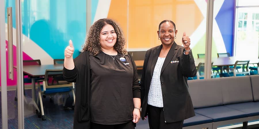 Two EdFed employees standing together with their thumbs up.