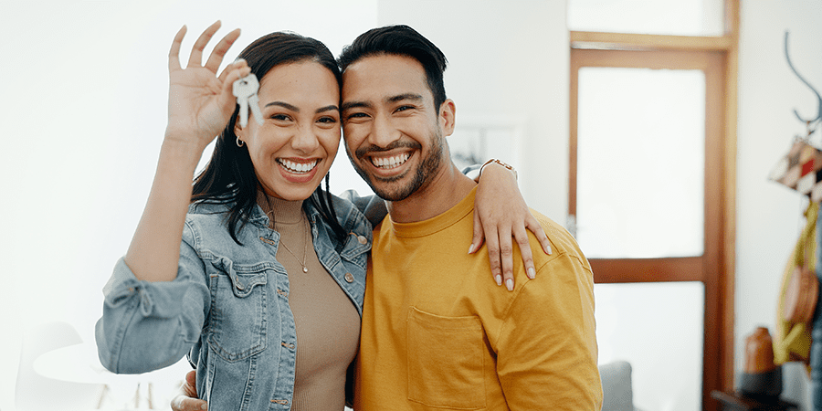 A young couple embracing eachother while the female holds keys.