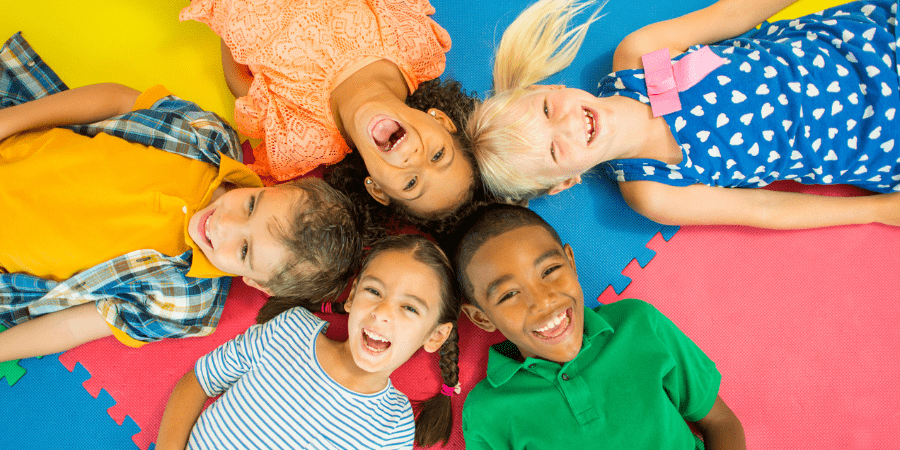 Overhead picture of a groupd of kids lying down together in a circle.