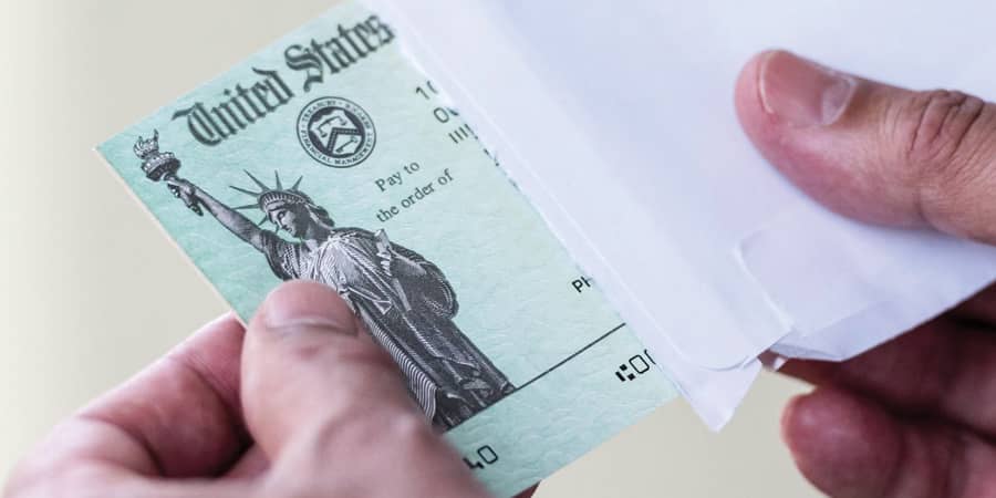 An IRS issued check being pulled out of an envelope.