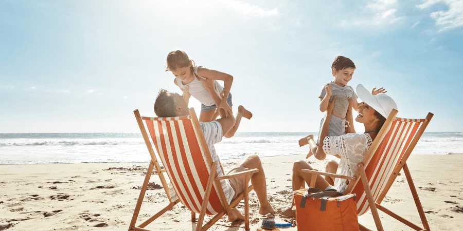 A family of four sitting on beach chairs and playing.