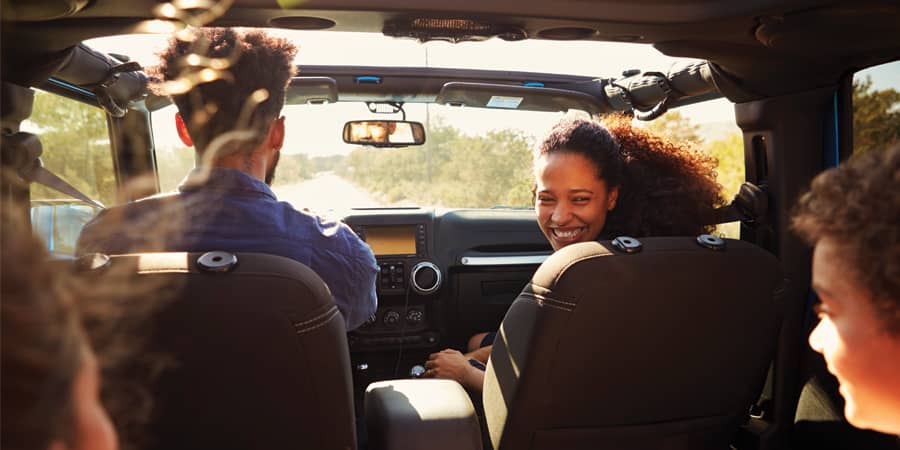 Young kids riding in a jeep with the roof open.