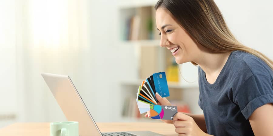 A woman sitting in front of a laptop while holding several cards.
