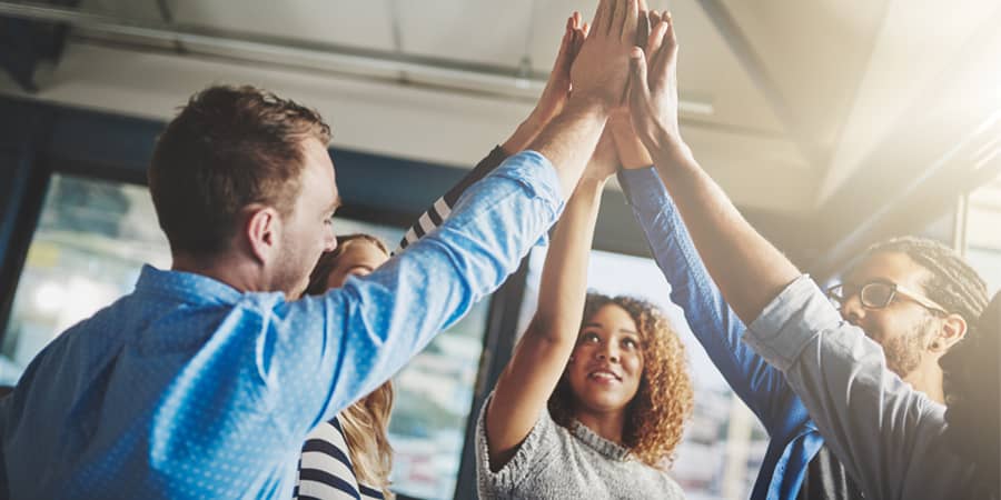 A group of employees in a circle with their hands together.