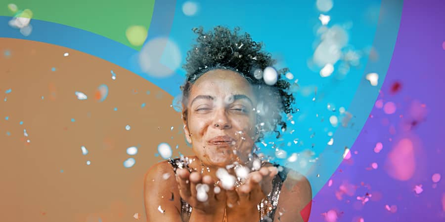A woman blowing bubbles against a colorful backdrop.