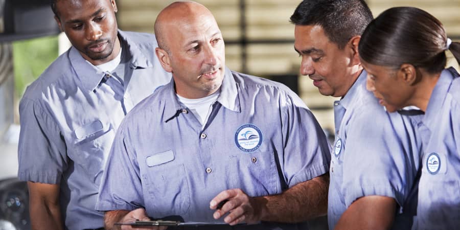 A group of maintenance professionals standing in a semi-circle collaborating.