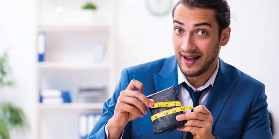 A young business man holding a wallet with a measuring tape around it.