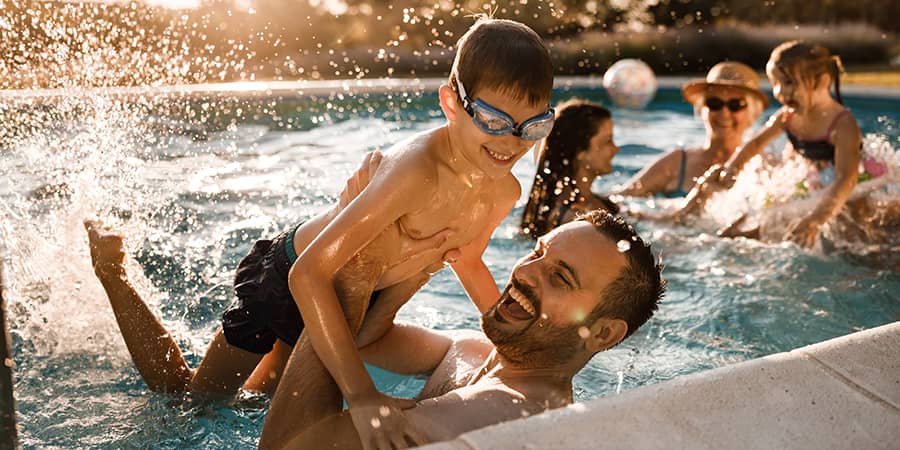 A father playing with his son on a pool.