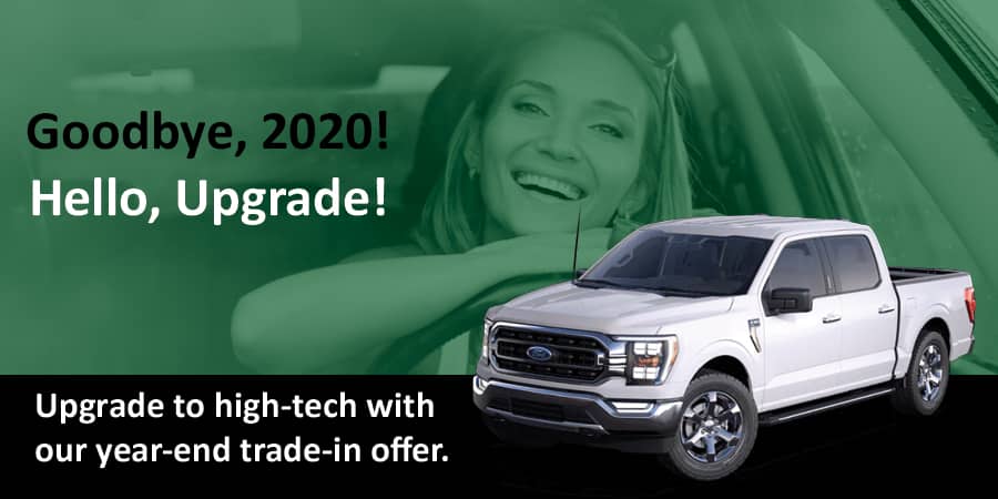 A woman sitting in her car with a big smile. To the left, the words: goodbye 2020! Hello, upgrade. At the bottom, the words: upgrade to high-tech with our year-end trade-in offer.