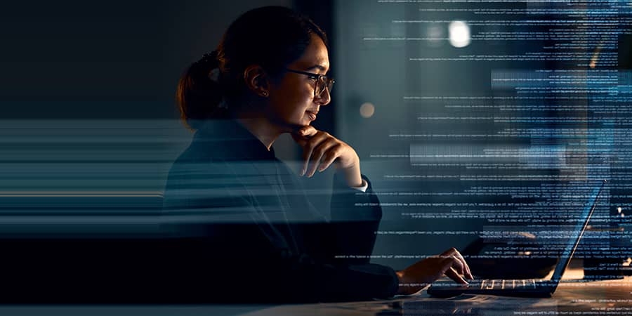 A woman using a laptop with lines of code as an overlay of the image.