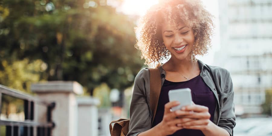 A young woman happily using a smartphone.