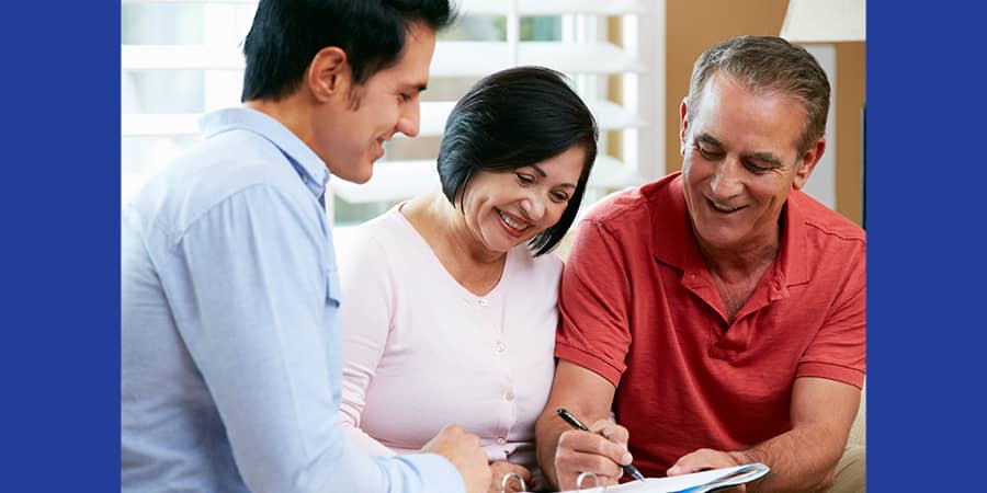 An elderly couple signing documents with an advisor.