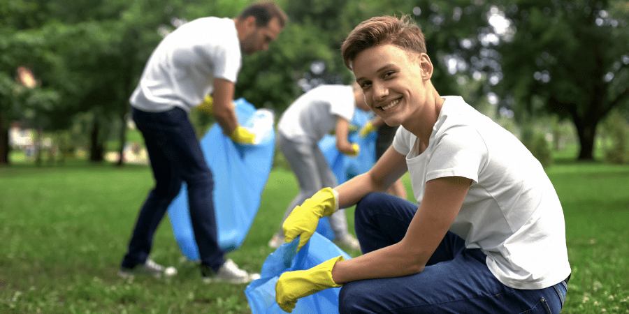 Students picking up trash in a green field.