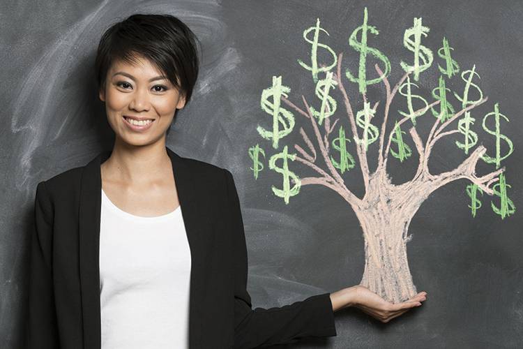 Woman standing against a blackboard with a money tree drawn with chalk.