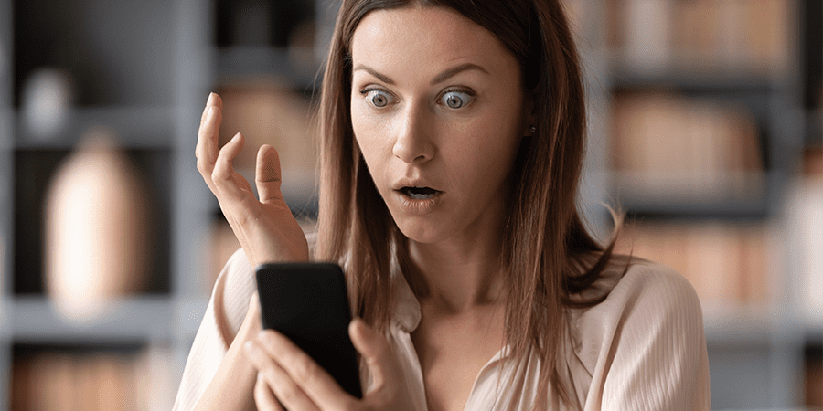 A young woman looking at her smartphone with a concerned expression.