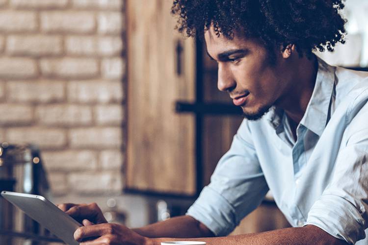 Man at a coffee shop looking at a tablet