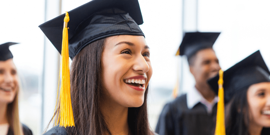 A young, female graduate wearing a graduation cap and gown.